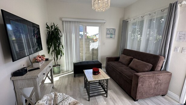 A living room with a flat-screen TV, a brown sofa, a patterned ottoman, a small table, and a potted plant. - Huntington Beach 2bed/2bath house.| Near Beach, Dining, Family Fun & Relaxation (Huntington Beach)