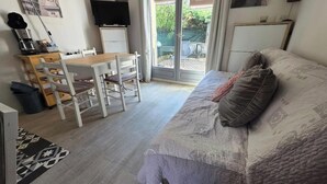 Een slaapkamer met een bed, een bureau met stoel, een televisie en een schuifdeur naar een terras.