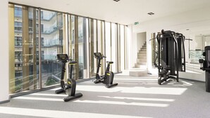 A modern gym with cardio machines, free weights, and a staircase leading to an upper level. - One Bedroom Apartment at The Lennox (Accra)