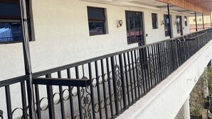 A building with a wooden sloped roof, white walls, and a black wrought iron balcony railing.