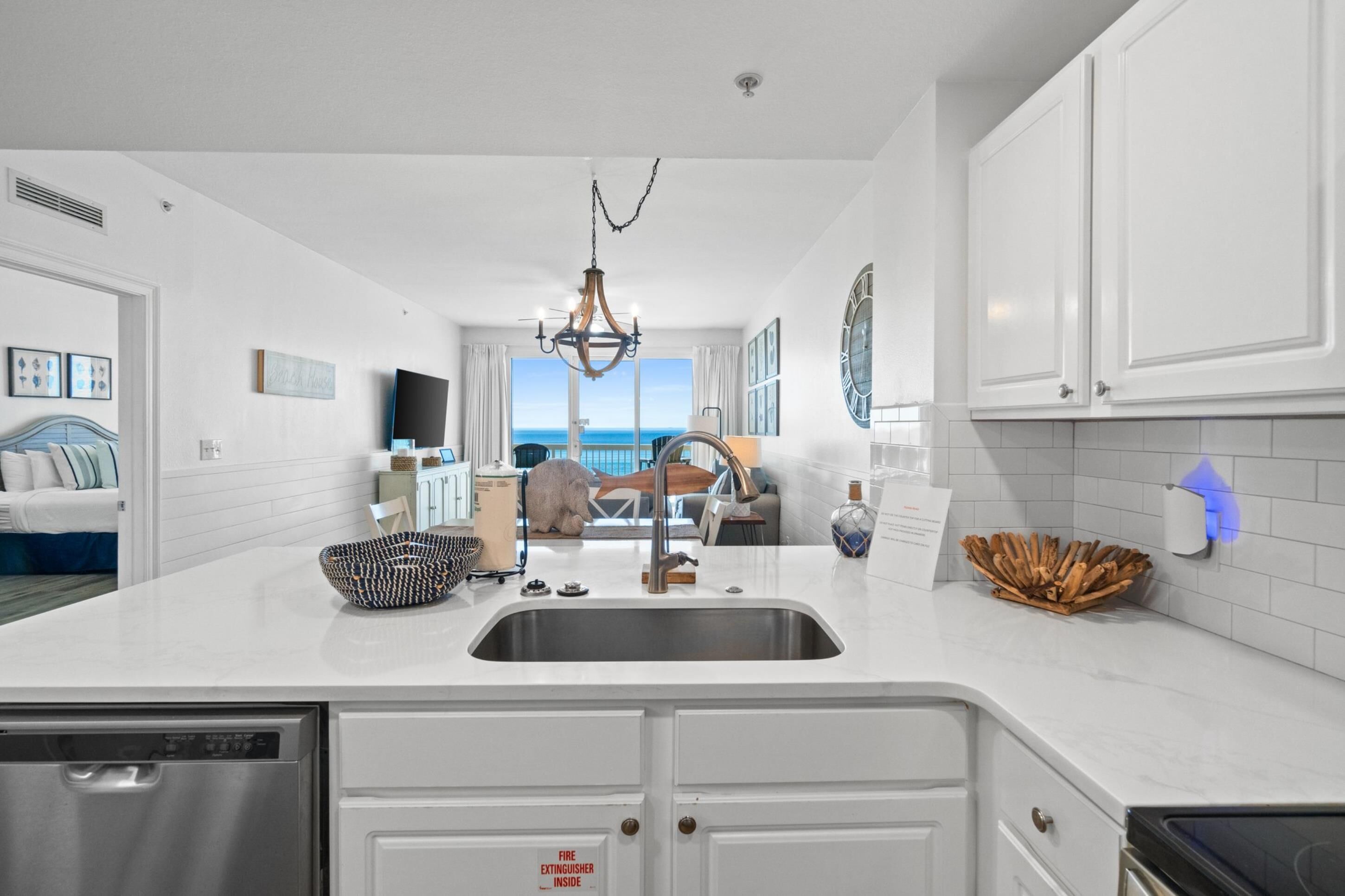 A modern kitchen with white cabinetry, a stainless steel sink, and a view to the outside.