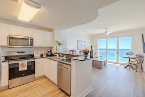 A modern kitchen with stainless steel appliances, a dining area with a view, and a balcony with a view.