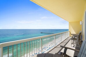 A balcony with a view of the ocean and beach, wooden furniture, and a yellow awning. - Calypso Beach Resort Tower 1 (Panama City Beach)