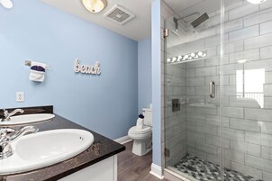 A bathroom with two sinks, a toilet, and a glass-enclosed shower.