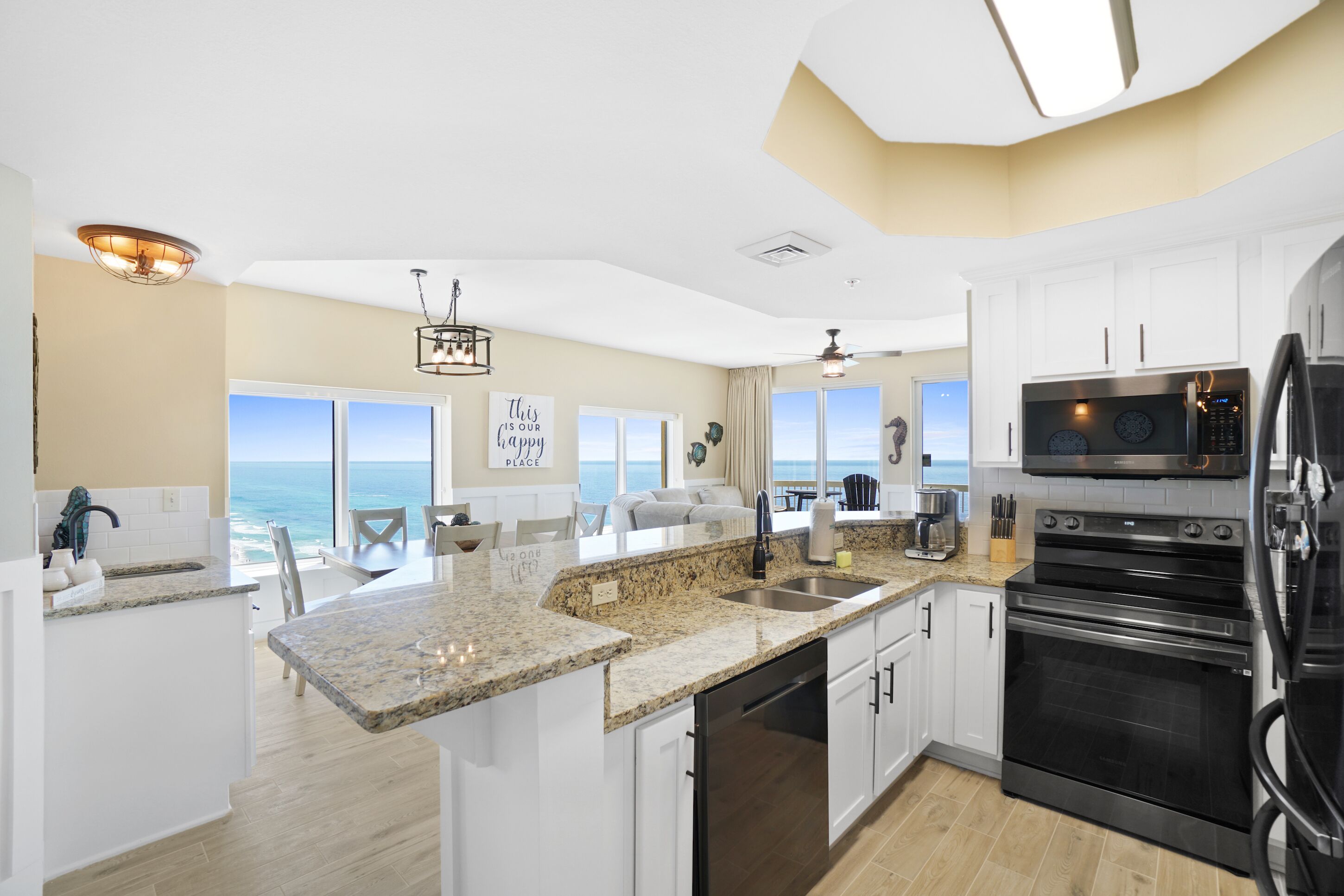 A modern kitchen with granite countertops, stainless steel appliances, and a view of the ocean.