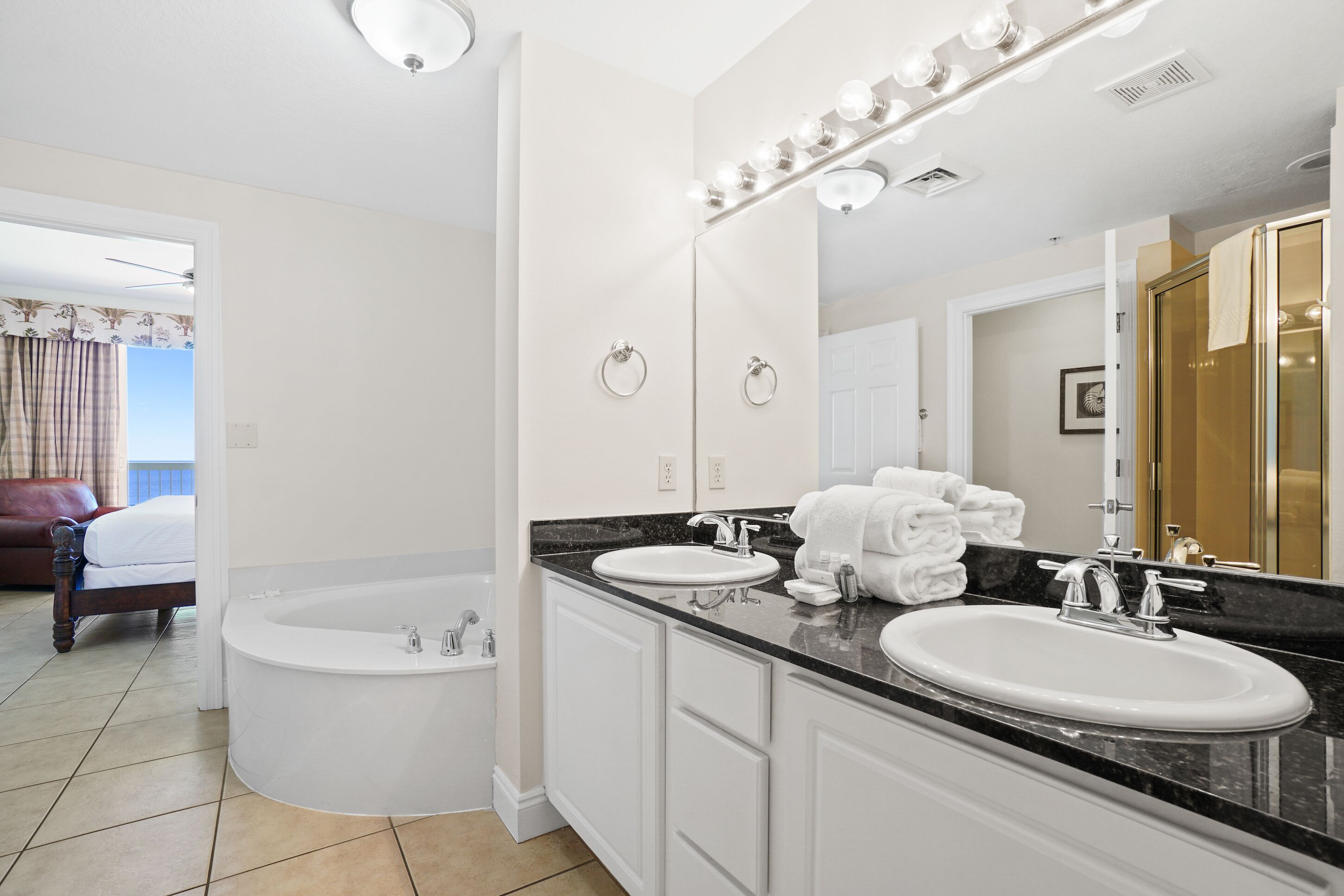 Une salle de bain moderne avec un double vasque, une baignoire et un grand miroir avec éclairage intégré.
