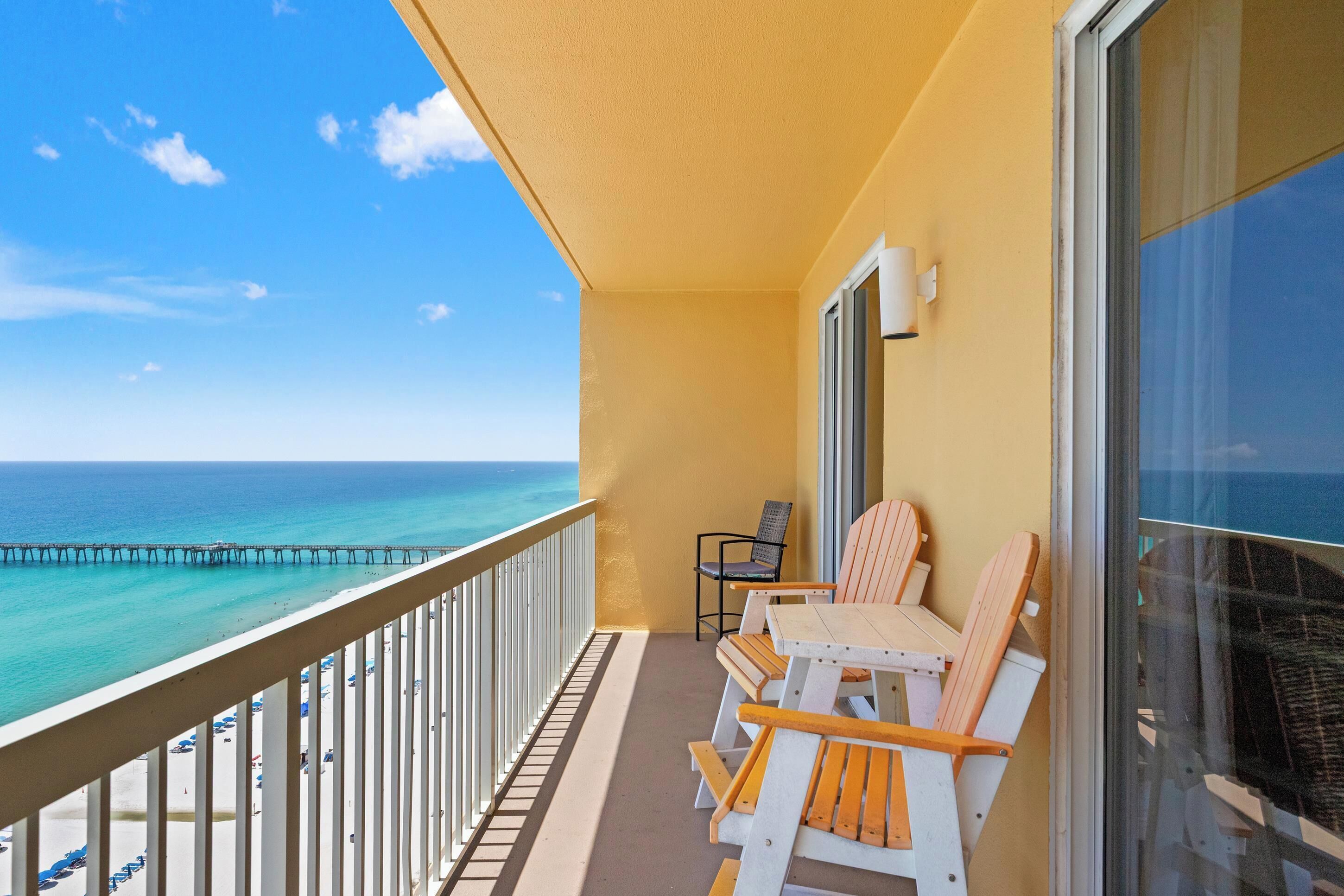 Un balcon avec vue sur l’océan, une table avec des chaises et une fenêtre.