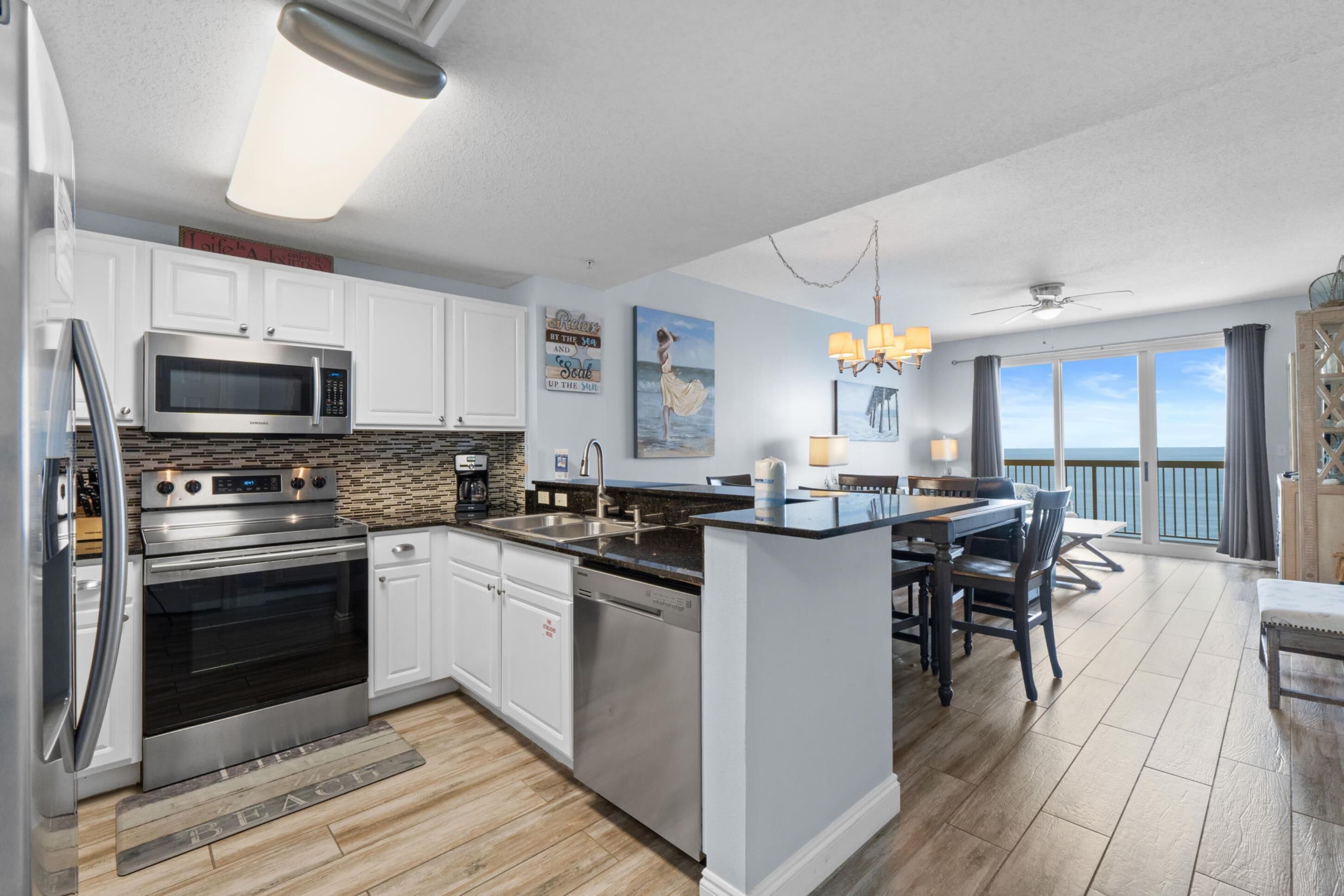 A modern kitchen with stainless steel appliances, a dining area with a view, and a balcony.