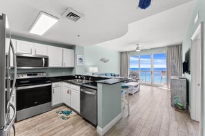 A modern kitchen with stainless steel appliances, a dining area with a view, and a balcony with a railing.