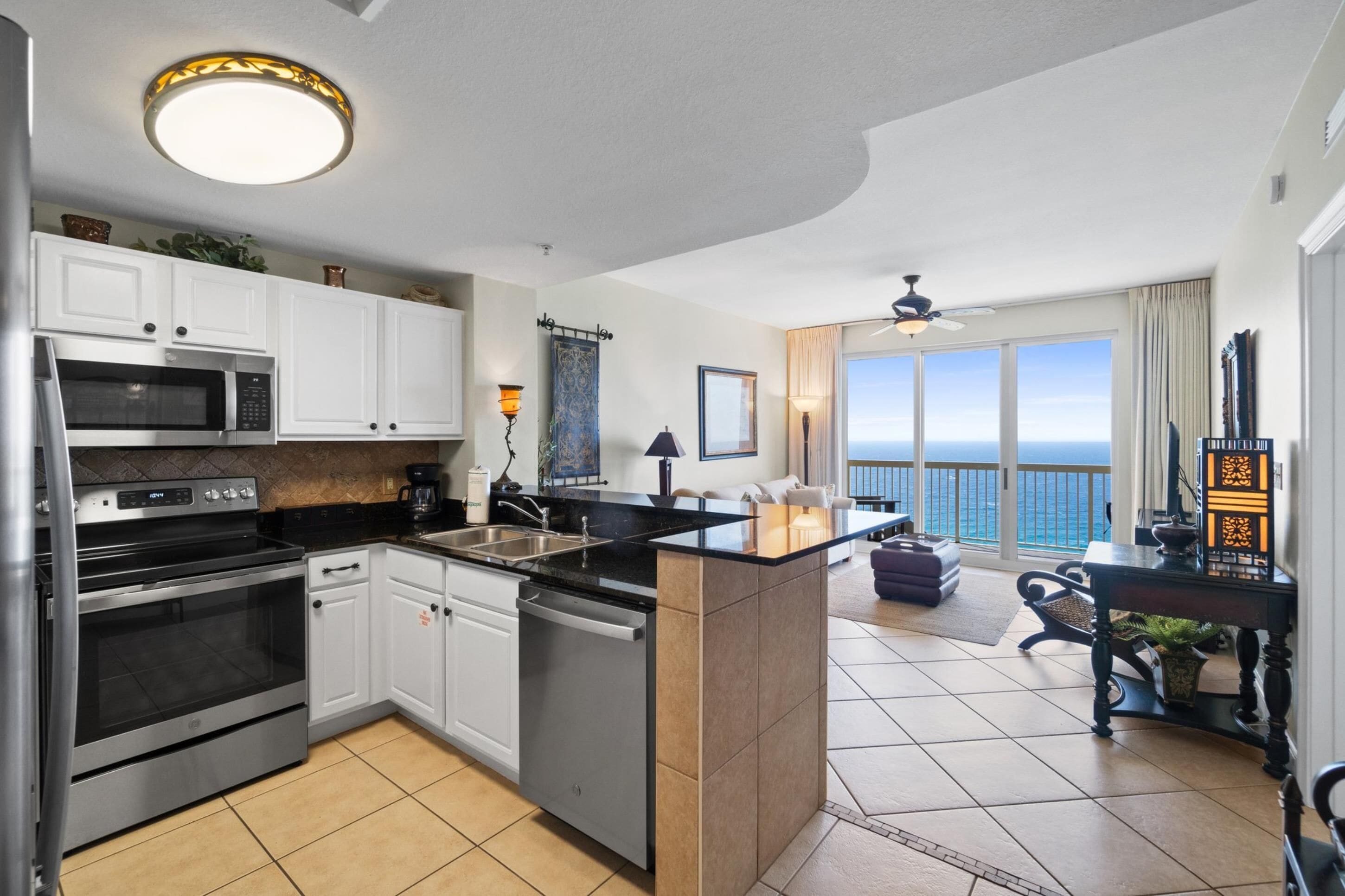 A modern kitchen with a central island, stainless steel appliances, and a view to the ocean.