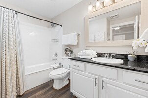 A modern bathroom with a bathtub, toilet, sink, and vanity.