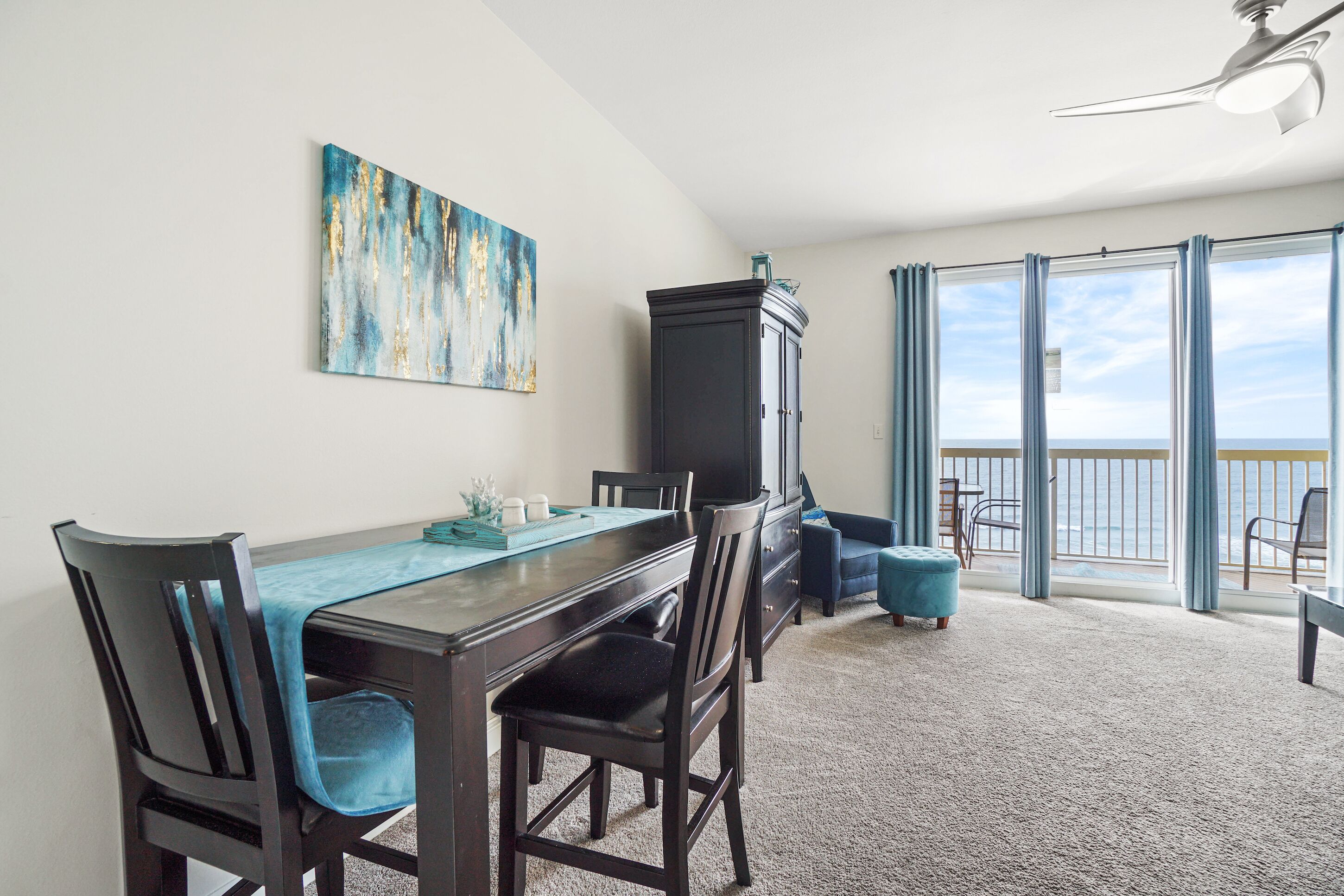 A dining area with a table, chairs, a cabinet, and a painting on the wall.