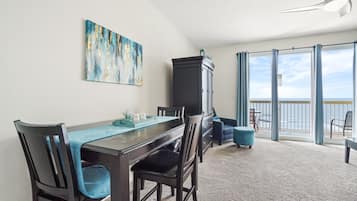 A dining area with a table, chairs, a cabinet, and a painting on the wall.