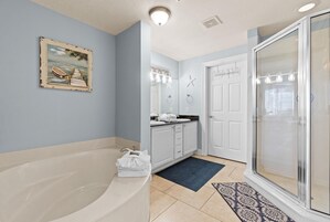 A bathroom with a bathtub, a shower, a sink with a mirror, and a door with a starfish decoration.