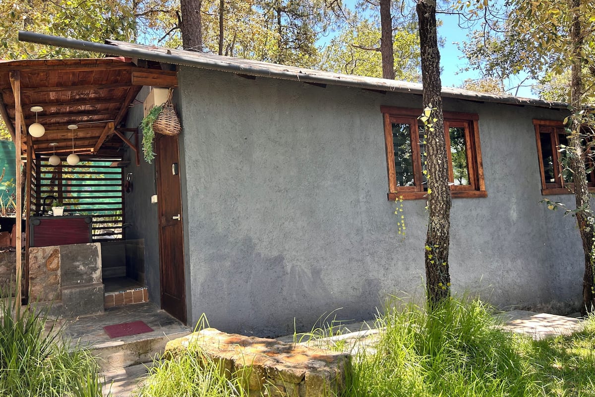 Eine rustikale Holzhütte mit einer Holzveranda, einem Steineingang und einer Betonfassade.