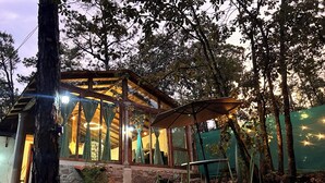 A rustic wooden cabin with large windows, a stone foundation, and a canopy umbrella. - Villas Bosque Alto By GEstores (Huasca de Ocampo)