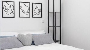 Una camera da letto con un letto, tre opere d'arte astratte alle pareti e un'alta libreria nera.