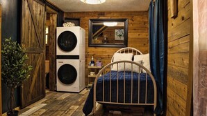 A compact room with a bed, a washing machine, and a mirror on the wall. - Peaceful Nature Retreat In Eureka Springs (Eureka Springs)
