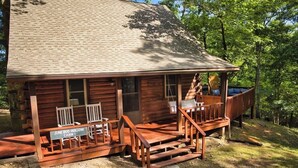 A rustic cabin with a porch, wooden benches, and a sign indicating 'June Bug Hollow Cabin 1'. - Peaceful Nature Retreat In Eureka Springs (Eureka Springs)