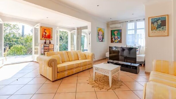 A spacious living room with a sofa, a TV, and artwork on the walls. - Villa Cannoise, Air-conditioned, Spacious, Sea view (Le Cannet)