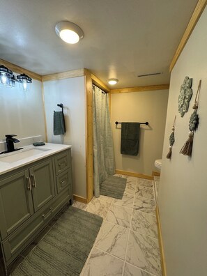Casa de banho com lavatório, espelho, porta-toalhas, cortina de chuveiro e decoração de parede.