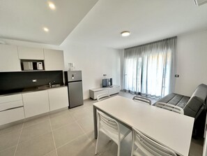 Eine moderne Küche mit weißen Schränken, einem Kühlschrank und einem Essbereich mit Tisch und Stühlen.