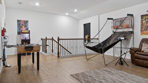 Una habitación con mesa de futbolín, pantalla de proyector y una silla.