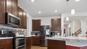 Una cocina moderna con armarios de madera, electrodomésticos de acero inoxidable y encimera de mármol.