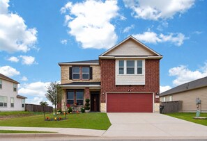 A two-story house with a red garage, a brick facade, and a clear blue sky.