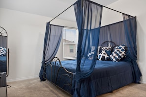 A four-poster bed with a canopy, a mirror, and patterned pillows.