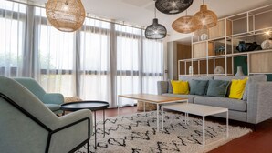 A modern living room with a sofa, armchair, coffee table, and pendant lights.