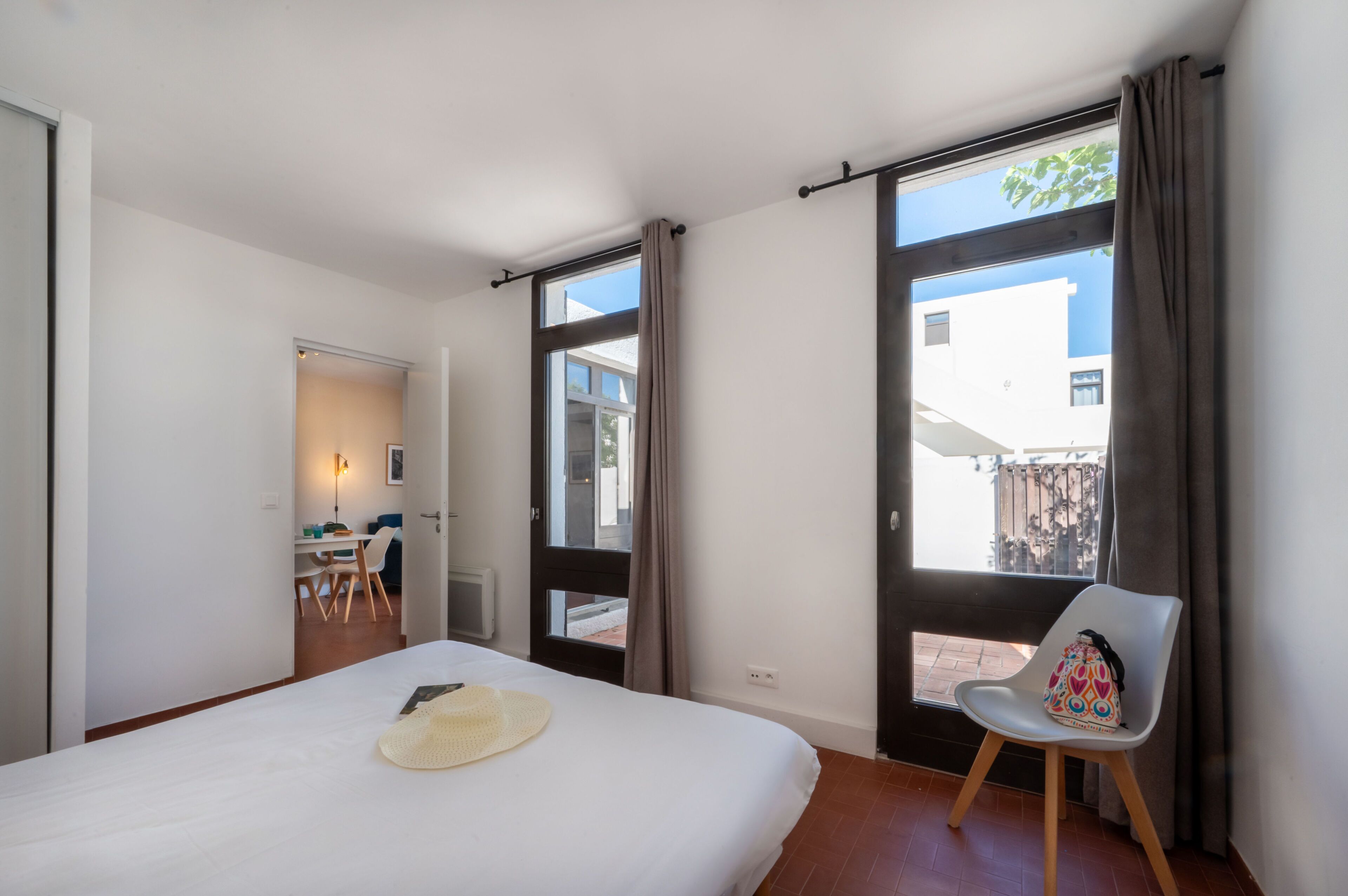 A bedroom with a bed, a chair, a desk, and a window with curtains.