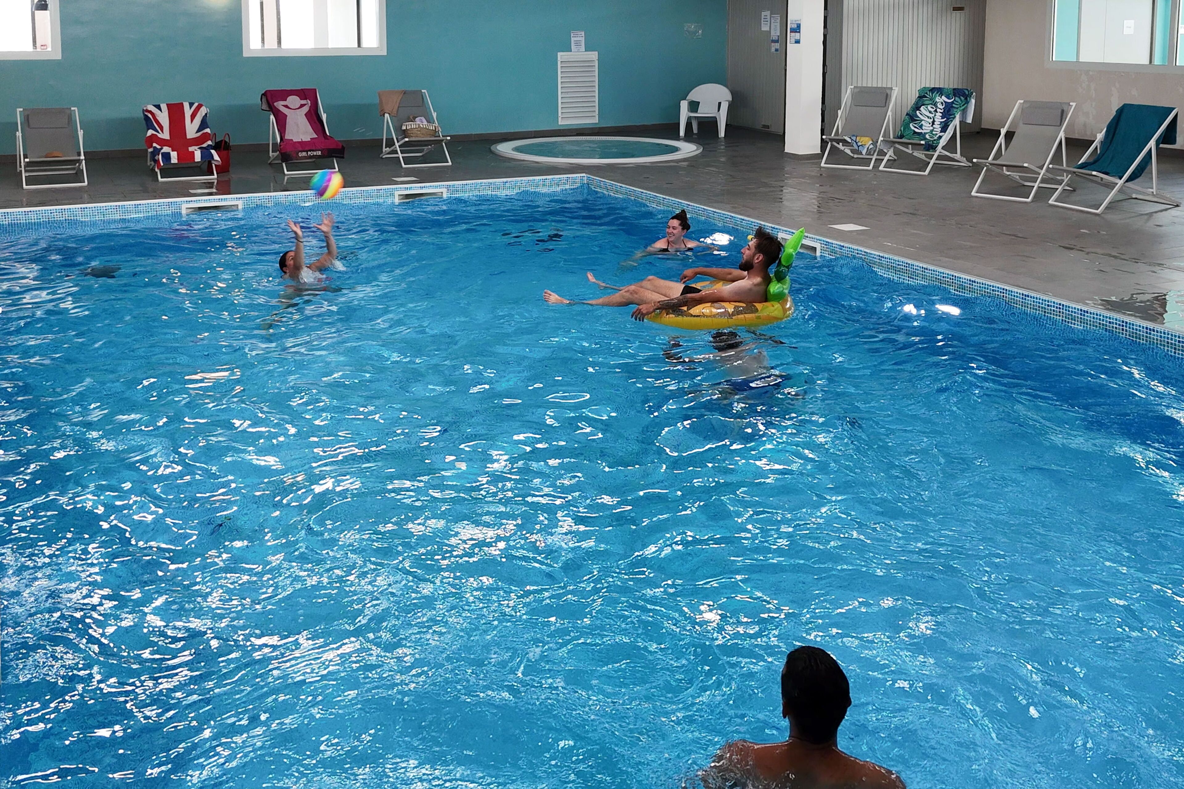 An indoor swimming pool with lounge chairs and a flag.
