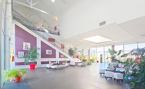 A spacious lobby with a staircase, seating area, and large windows.