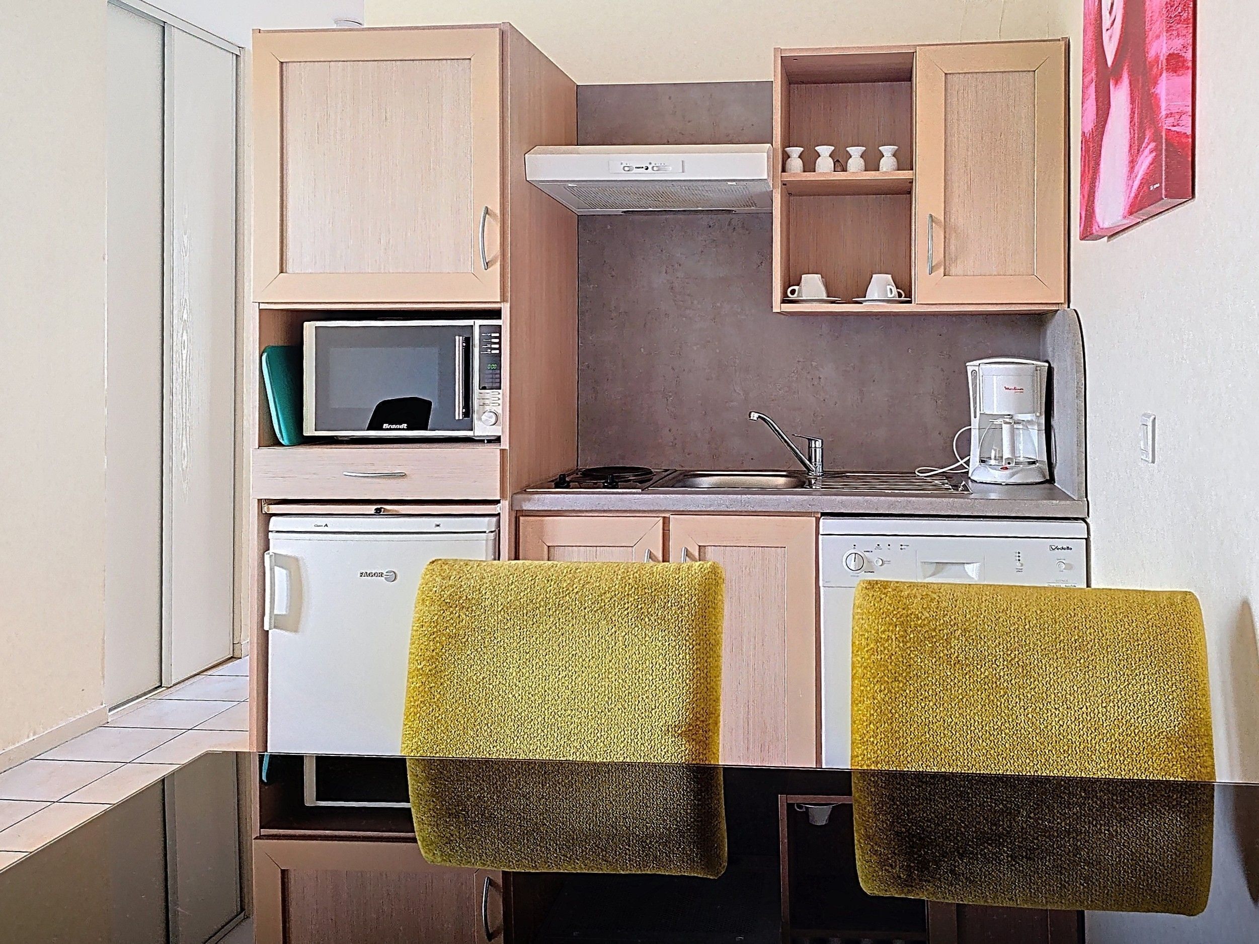 Een kleine keuken met een magnetron, fornuis, spoelbak en koffiezetapparaat.