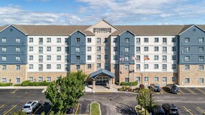 Ein Staybridge Suites Hotel mit einem zentralen Eingang, mehreren Etagen und einem Parkplatz.