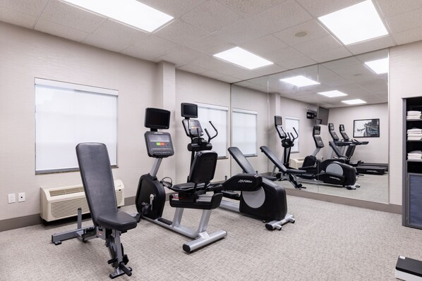A gym with stationary bikes, a treadmill, and a weight bench.