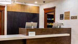 A reception desk with two HP laptops, a sign reading 'IHG One Awards,' and a security camera above.