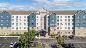 Un hotel Staybridge Suites con entrada principal, varios pisos y estacionamiento.