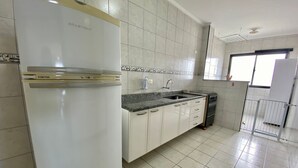 Eine Küche mit weißen Schränken, einer Granit Arbeitsplatte, einem Edelstahl Kühlschrank und einem Gasherd.