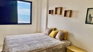 Ein Schlafzimmer mit einem Bett, einem Fenster, einem Nachttisch und Wandregalen.