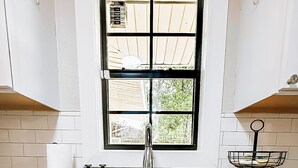 A kitchen with a double sink, a window with a view, and a countertop with a soap dispenser. - Modern House Near ACU, HSU, Hendrick North (Abilene)