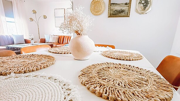 A dining area with a white table, woven placemats, and a vase with dried flowers. - Modern House Near ACU, HSU, Hendrick North (Abilene)