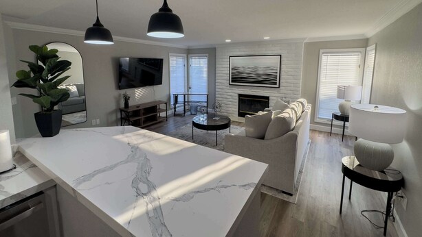 A modern living room with a marble island, a sofa, a fireplace, and a television. - One Bedroom,  First Floor (Wichita)