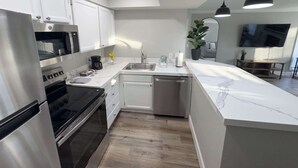 A modern kitchen with stainless steel appliances, a marble countertop, and a built-in dishwasher. - One Bedroom,  First Floor (Wichita)