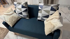A dark blue sofa with geometric patterned pillows and fluffy throw pillows. - Le Cocon : Bright studio 32m² + free private parking (rare). Near Stadium (Troyes)