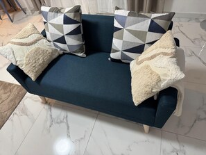 A dark blue sofa with geometric patterned pillows and fluffy throw pillows.