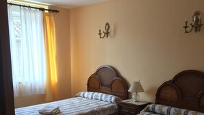 Una stanza con due letti di legno, un tavolino e una sedia.