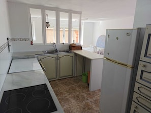 Una cocina con estufa, pileta y refrigerador.