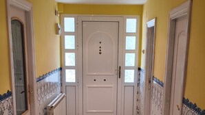 Un corridoio con una porta bianca, pavimento piastrellato e pareti gialle.